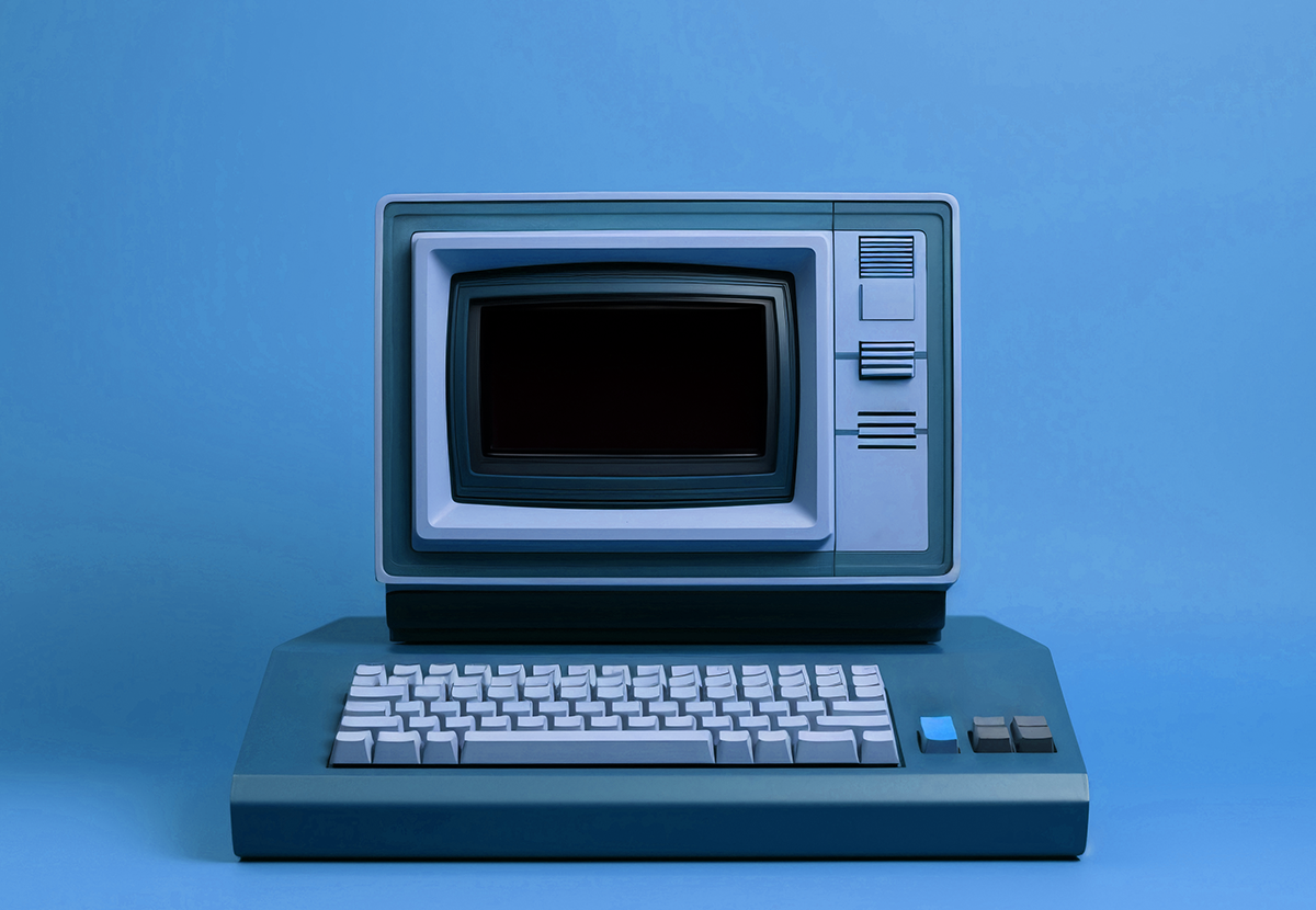 Ein älterer Retro-Computer mit Tastatur und kleinem Röhren-Bildschirm auf einem blauen Hintergrund mit leichtem Verlauf