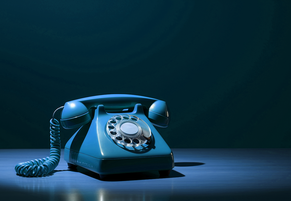 Ein bläuliches Telefon in einem Spot-Licht auf einem blauen Hintergrund mit deutlichen Schattierungen